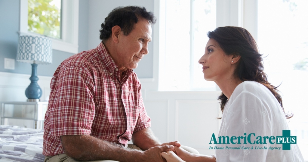 A daughter who is caregiving for her dad who has Alzheimer’s disease, lovingly holds his hands.