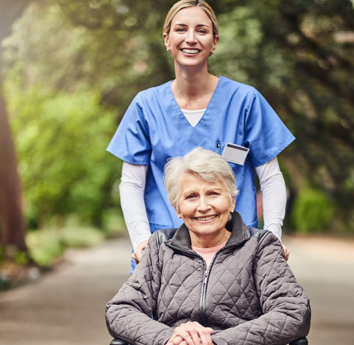 A professional caregiver wheels a client on a walk while both are smiling, representing how Anthem Personal Home Helper can help seniors in Lexington, VA