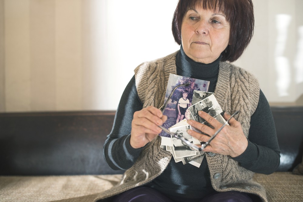 A senior woman holds pictures, representing dementia and the kind of people that dementia care services in Mecklenburg County, VA can help with.