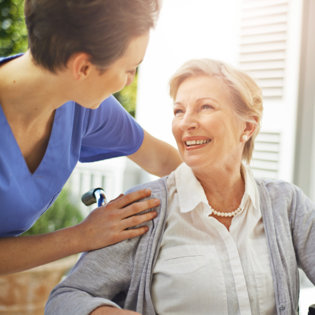 Companion Care Mecklenburg A professional caregiver helps a senior client as they both smile, representing how companion care in Mecklenburg County can help.