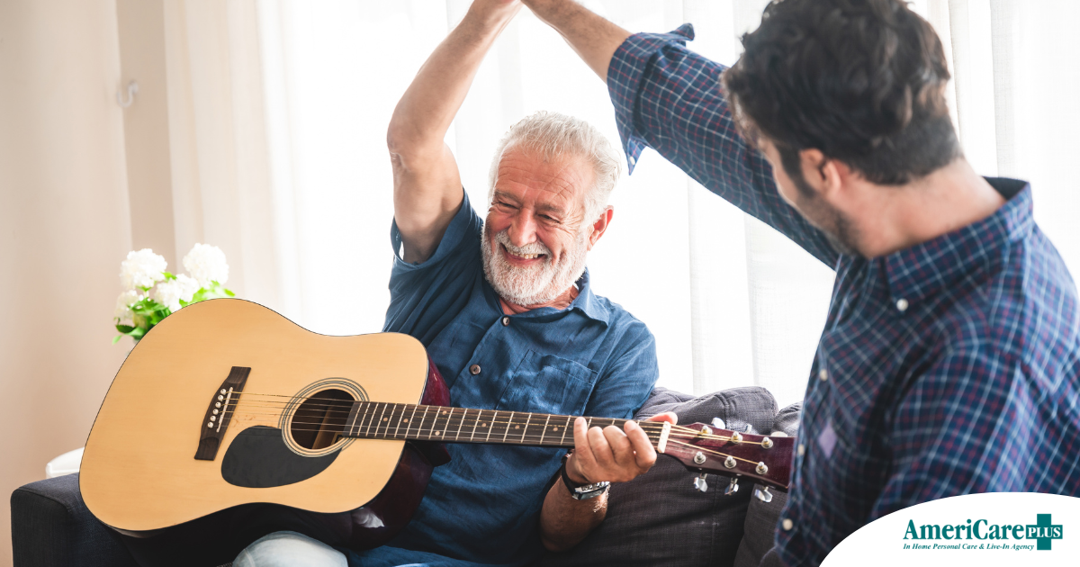 A smiling son high fives his happy elderly father as he plays the guitar, showing the positive effect music can have on people, including those with dementia.