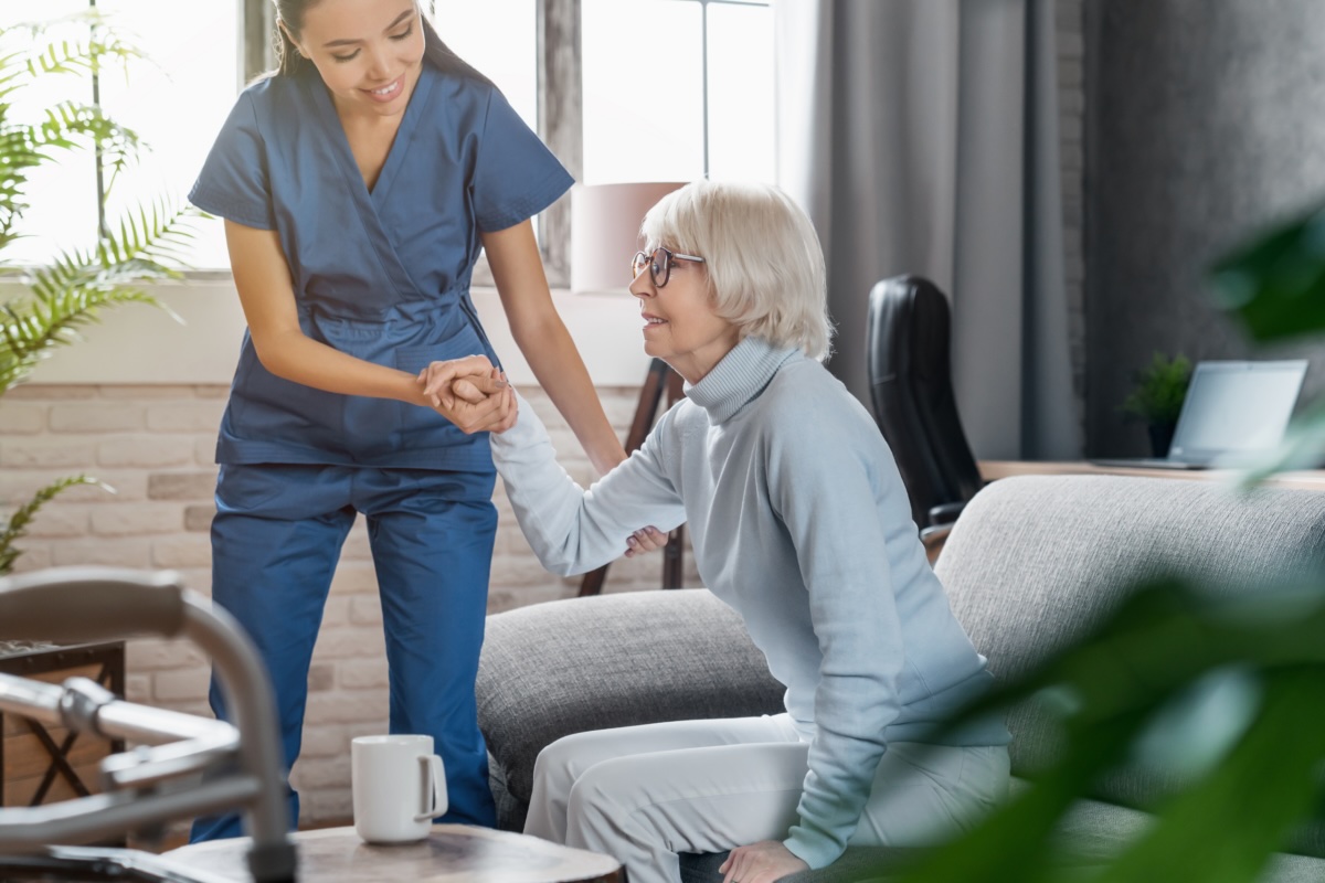 A caregiver compassionately helps an older client, representing companion care in Orange.