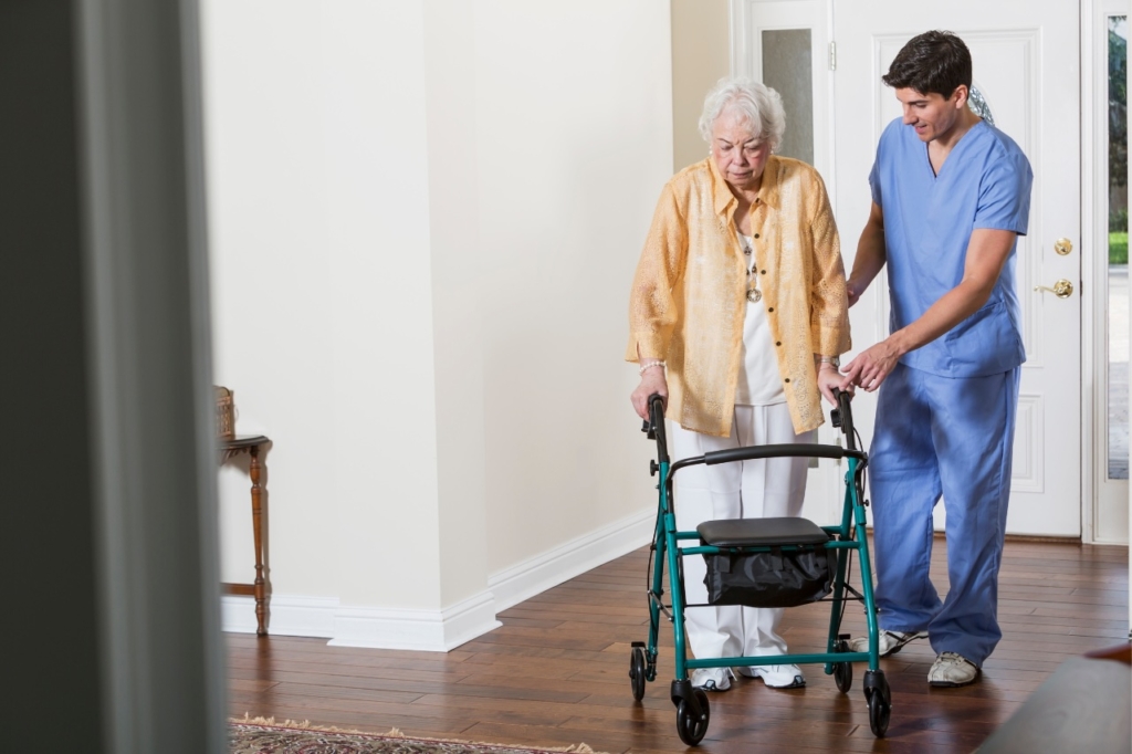 A caregiver helps an older client who has a walker, representing the kind of help post-operative care in Orange, VA can provide.