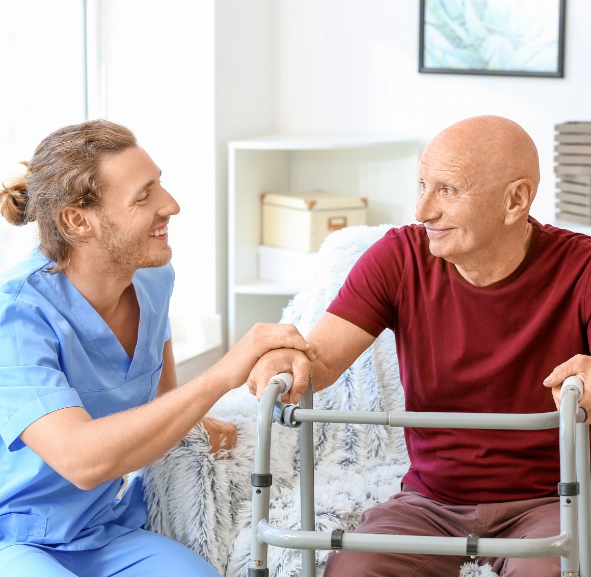 A caregiver smiles with an older client who has a walker, representing the kind of help post-operative care in Orange, VA can provide.