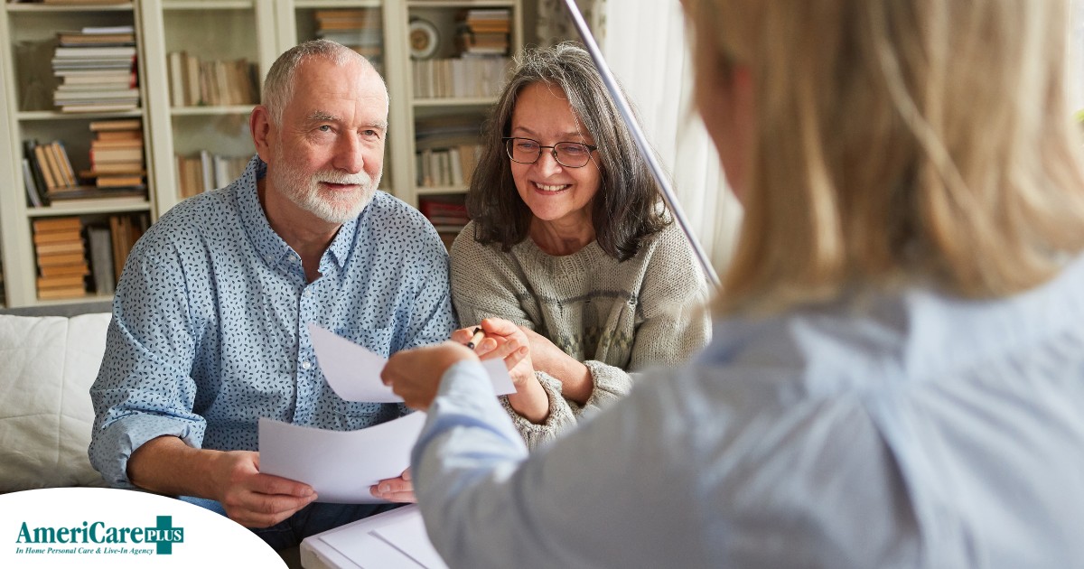 An older couple receives and considers papers from a woman, representing someone considering long-term care insurance.