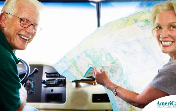 An older couple looks back smiling from the front of an RV, representing how day trips for seniors can help boost the mood of everyone.