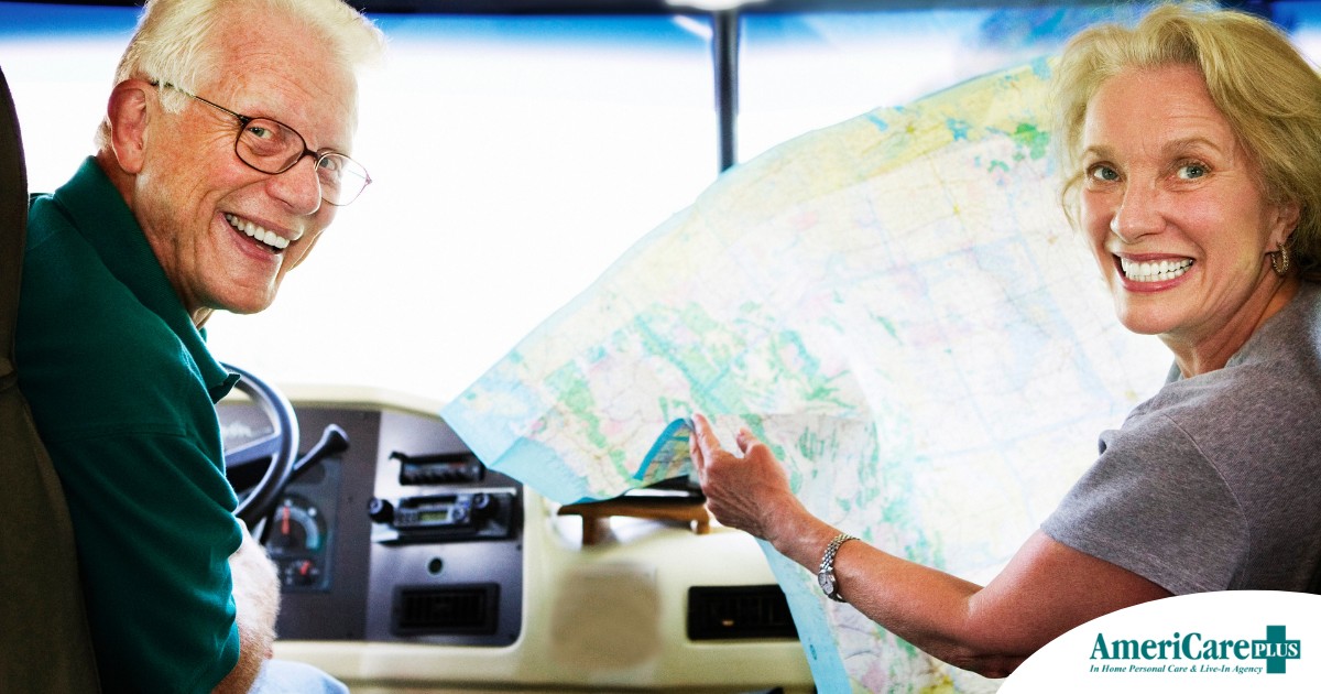 An older couple looks back smiling from the front of an RV, representing how day trips for seniors can help boost the mood of everyone.