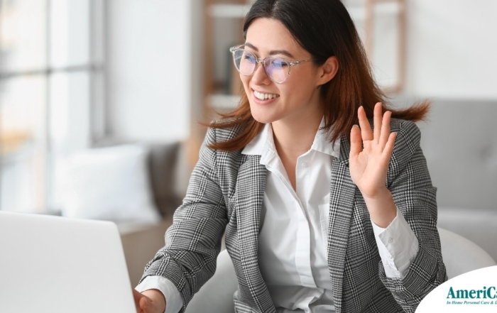 A well-dressed woman smiles and says hi on a videoconference, representing a candidate who is well-prepared for a caregiver interview.