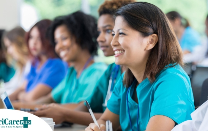 Several students in scrubs happily attend a class, representing caregiver training.